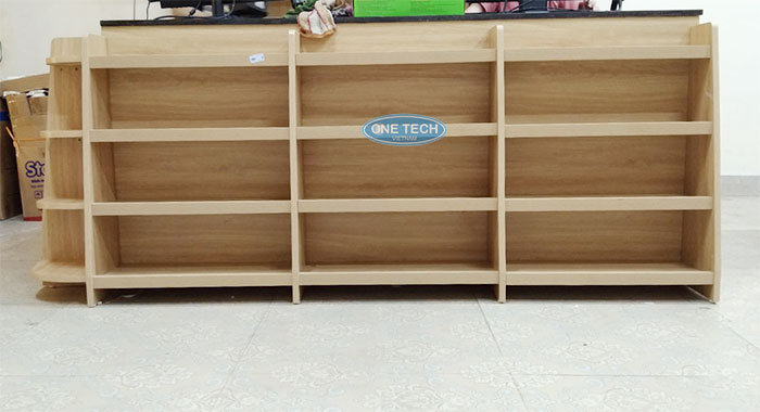 Mẫu bàn thu ngân siêu thị có kệ gỗ bày hàng phía trước